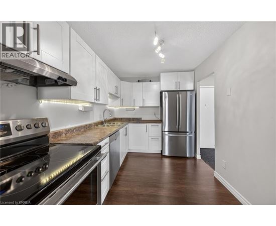 A kitchen with white cabinets and a stainless steel refrigerator.