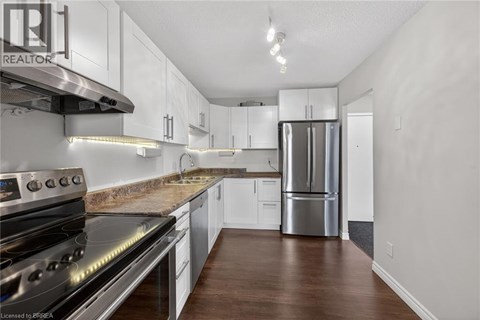 A kitchen with white cabinets and a stainless steel refrigerator.