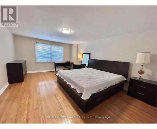 A bedroom with a bed, nightstand, and a window with blinds.