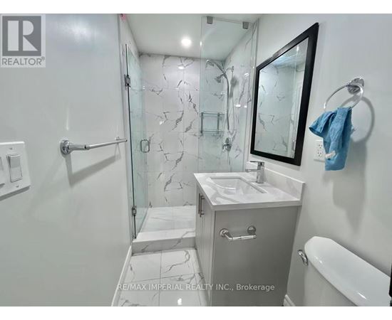 A bathroom with a marble tile shower and a white sink vanity.