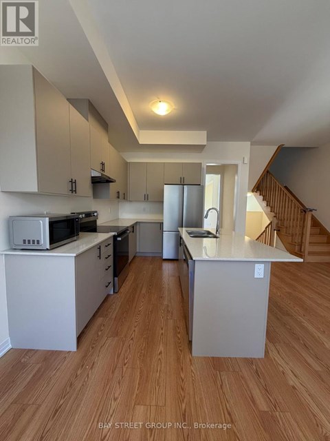A kitchen with white cabinets and a microwave on top of the counter.