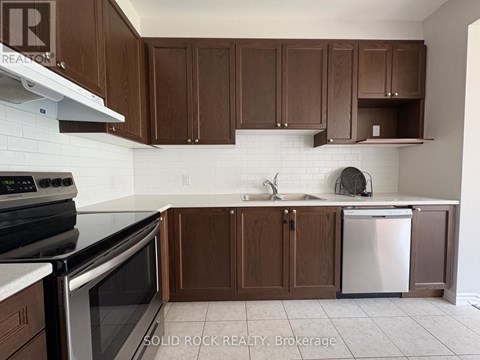 A kitchen with brown cabinets and a white tile backsplash.