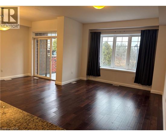 A room with wooden flooring and a window with black curtains.