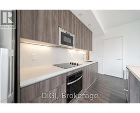 A modern kitchen with a refrigerator, microwave, and oven.