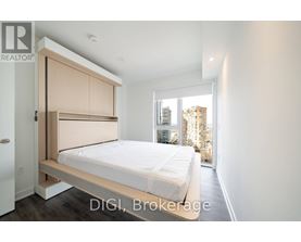 A bedroom with a bed, a wardrobe and a window overlooking a cityscape.