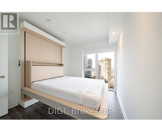 A bedroom with a bed, a wardrobe and a window overlooking a cityscape.