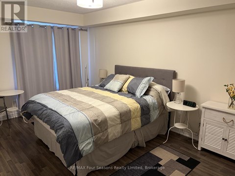 A bedroom with a large bed and a nightstand with a lamp.