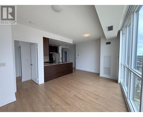 A spacious room with wooden flooring and a large window on the right side.