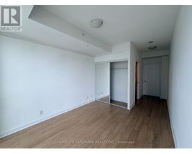 A room with wooden flooring and white walls, with a doorway leading to another room.