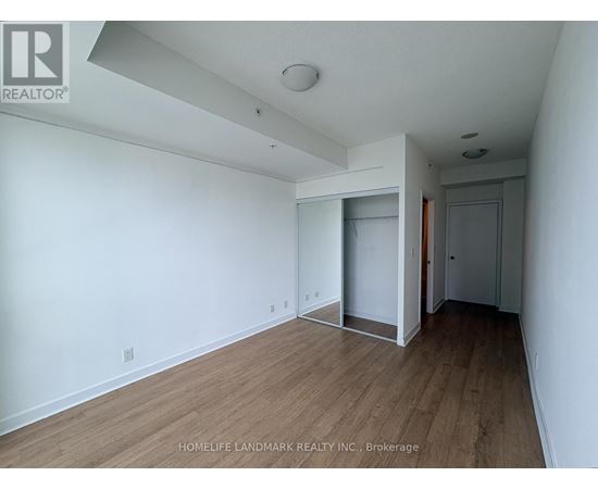 A room with wooden flooring and white walls, with a doorway leading to another room.