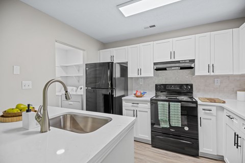 A kitchen with white cabinets and a black oven.