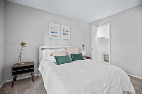 A bedroom with a white bed and a lamp on a table.
