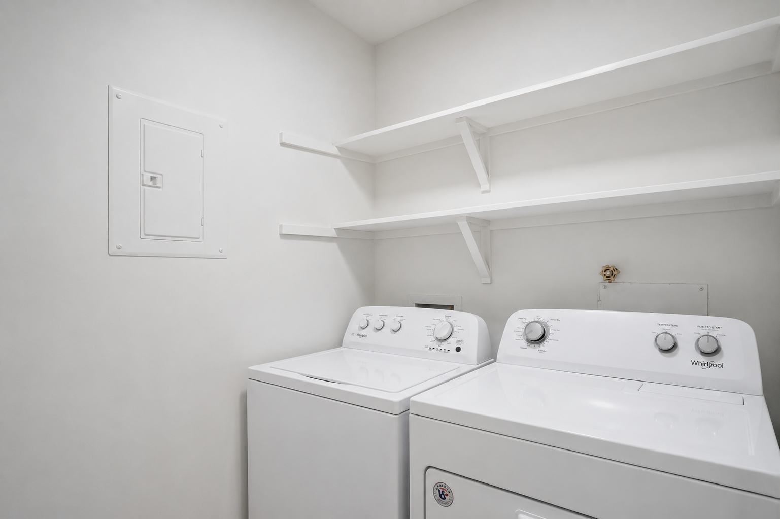 Two white washing machines in a laundry room.