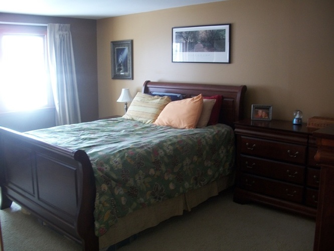 A bedroom with a bed, dresser, and window.