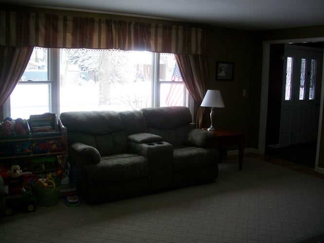 A living room with a grey couch and a lamp.