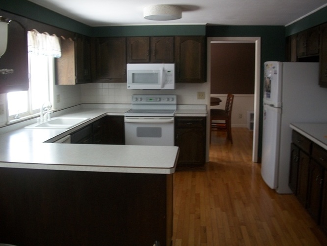 A kitchen with a white counter top and a white fridge.