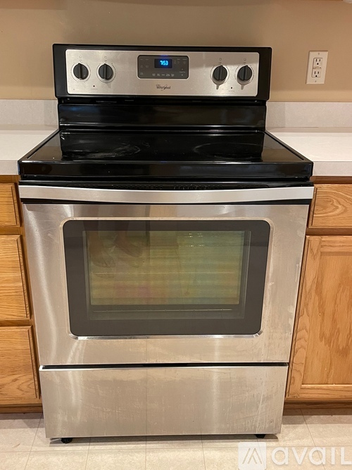 A stainless steel oven with a digital control panel is installed in a kitchen.