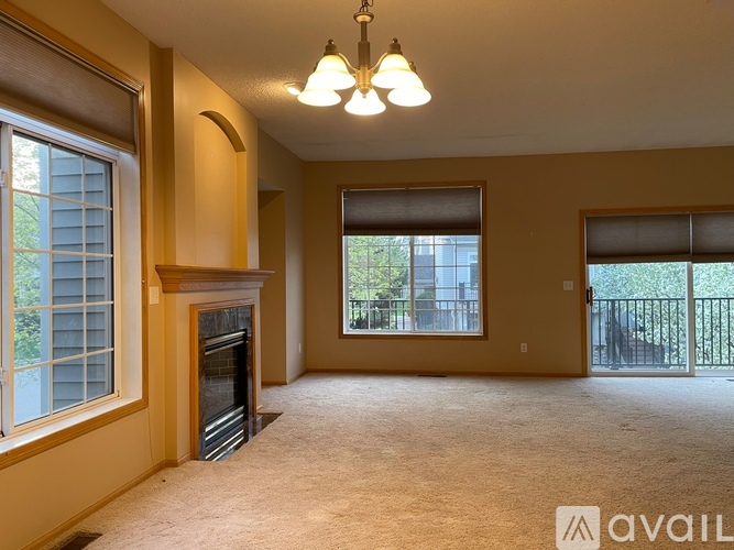 A spacious living room with a fireplace and large windows.