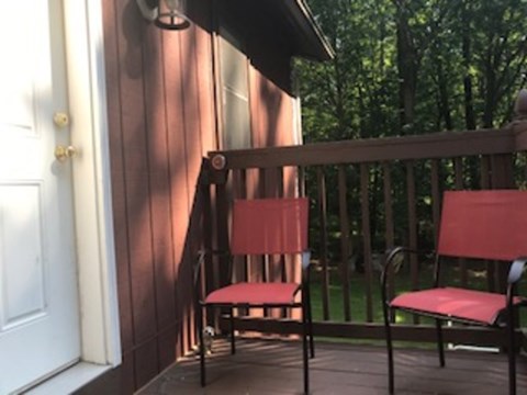 Two red chairs on a wooden deck.