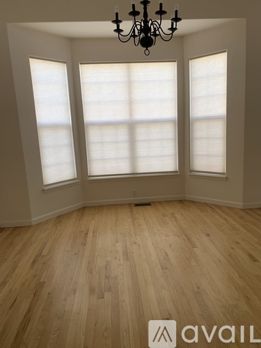 A chandelier hangs from the ceiling in a spacious room with a staircase.