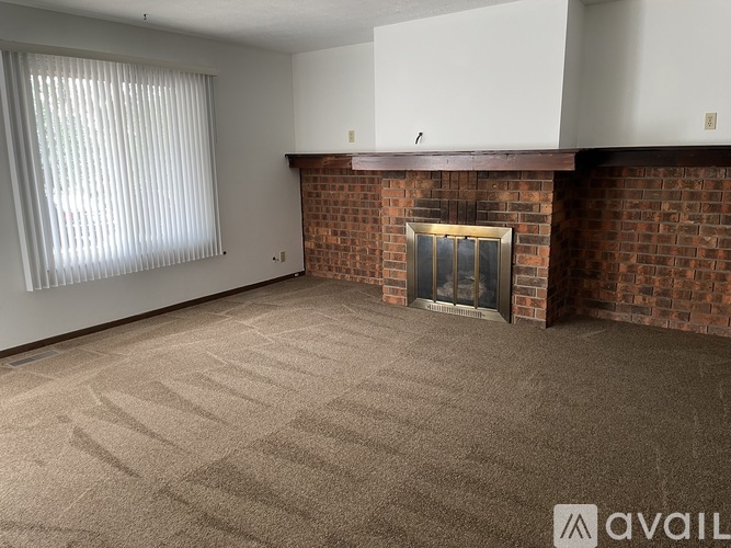 A room with a fireplace and a window with blinds.