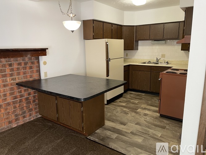 A kitchen with a black countertop and brown cabinets.