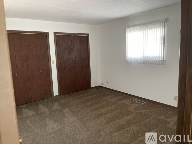 A room with two brown doors and a carpeted floor.
