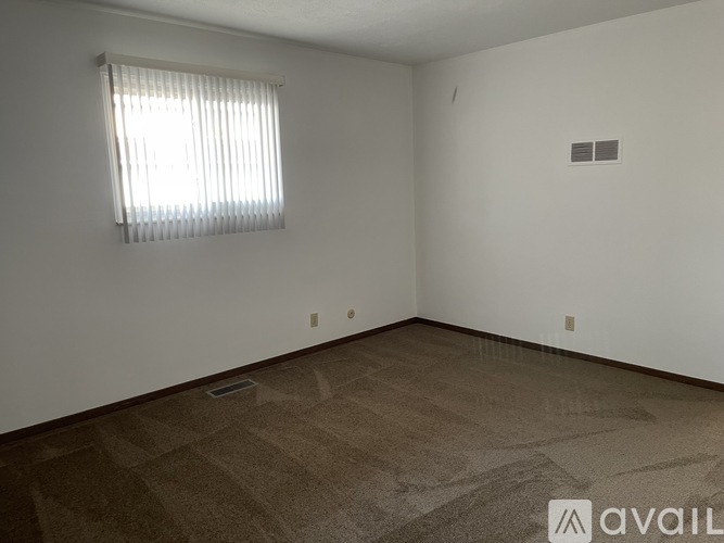 A room with a window and a carpeted floor.