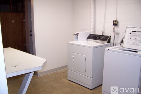 A white table and a white cabinet are in a room with a white wall.