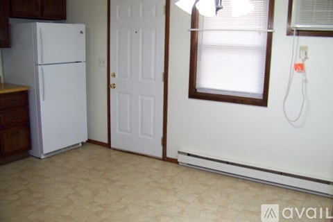 A kitchen with a white fridge and a white door.