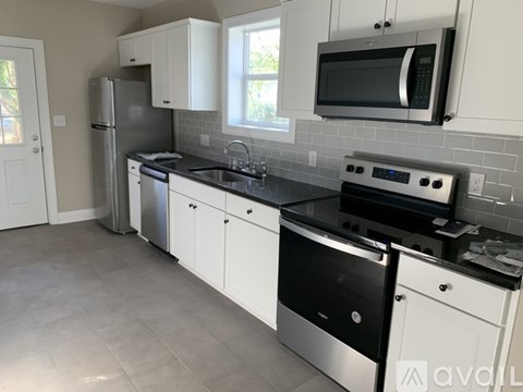 A kitchen with white cabinets and black countertops.