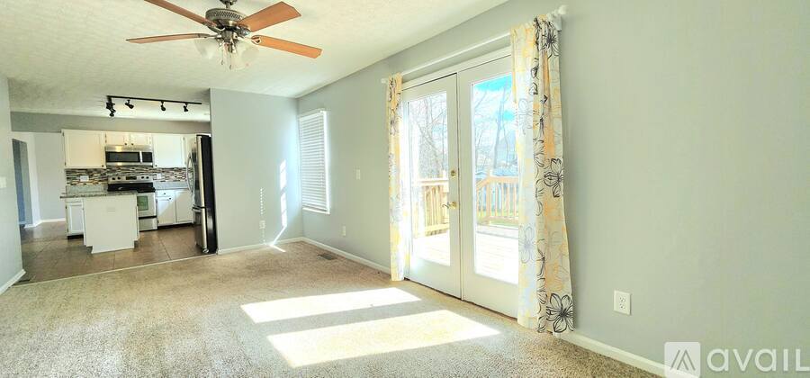 A living room with a ceiling fan and sliding glass doors leading to a deck.
