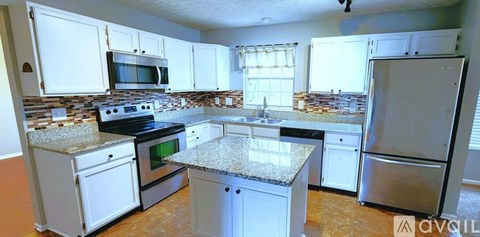 A kitchen with white cabinets and granite countertops.