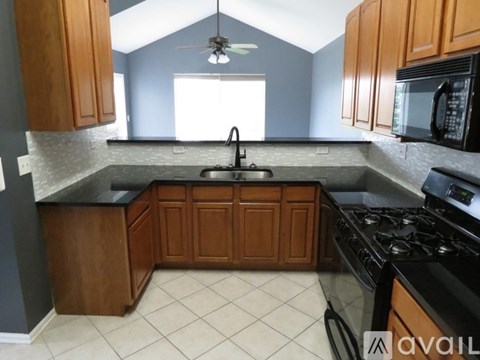 A kitchen with wooden cabinets and black appliances.