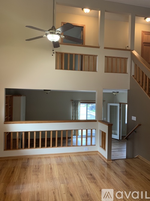 A living room with a ceiling fan and wooden floors.