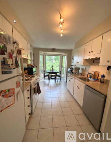 A kitchen with white cabinets and a refrigerator with magnets and notes on it.