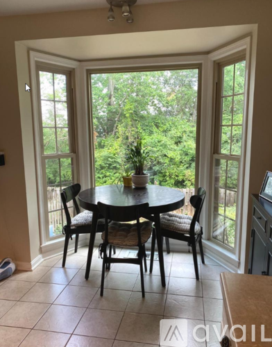 A dining room with a table and chairs in front of a sliding glass door.