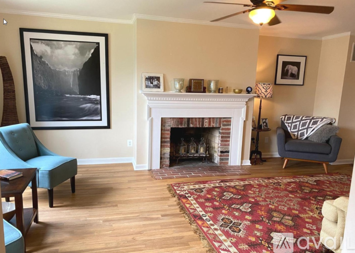 A living room with a fireplace, a chair, and a painting on the wall.