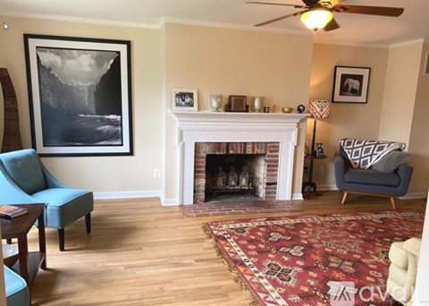 A living room with a fireplace, a chair, and a painting on the wall.