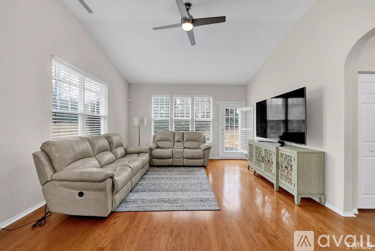 A living room with a grey sofa and a television on a cabinet.