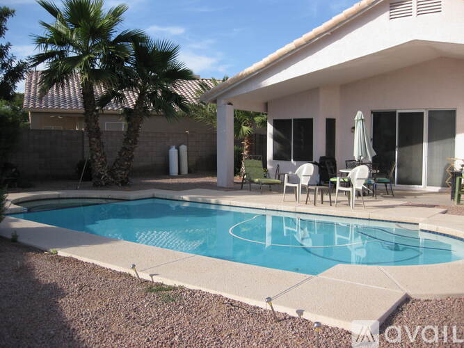 A pool in a backyard with a house and palm tree.