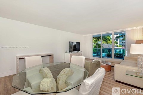 A modern living room with a glass table and white chairs.