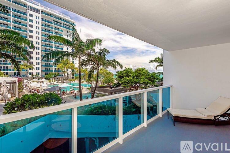 A balcony with a chair and a view of a pool and buildings.