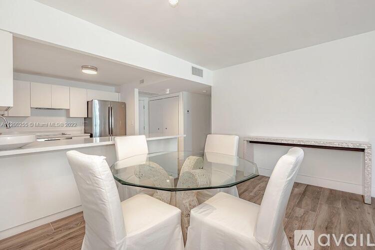 A modern dining room with a glass table and white chairs.