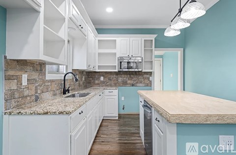 A kitchen with white cabinets and a granite countertop.