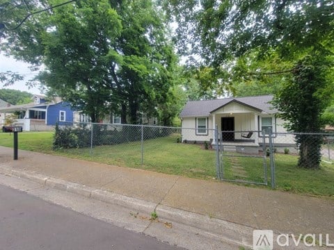 A house with a blue house in the background and a fence in front of the house.