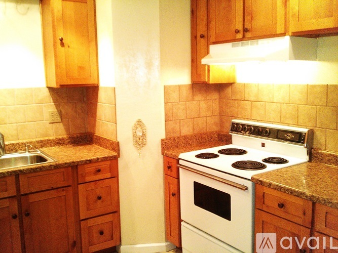 A kitchen with wooden cabinets and a white stove top oven.