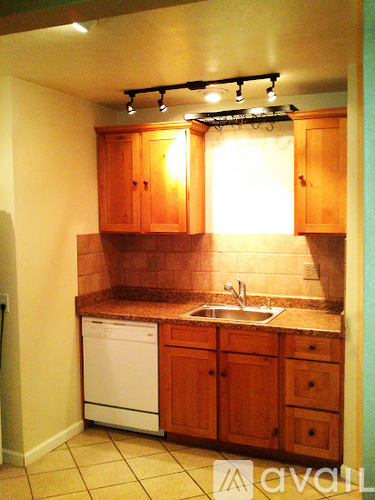 A small kitchen with wooden cabinets and a white dishwasher.