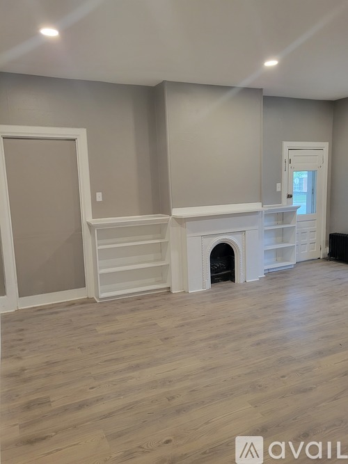 A room with a fireplace and wooden flooring.