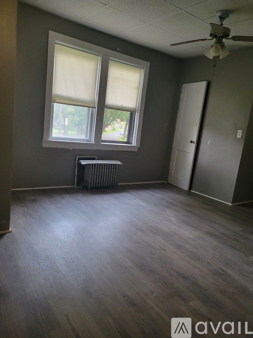 A room with a ceiling fan and a window with blinds.